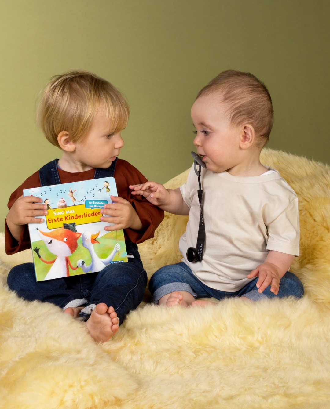 Baby mit Buch auf Lammfell